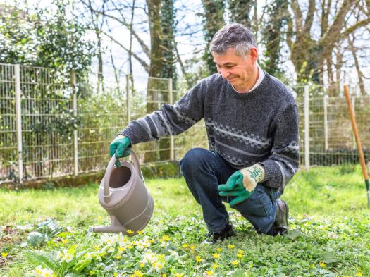 Un homme avec un arrosoir, lors d'un atelier de jardinage dans une délégation locale